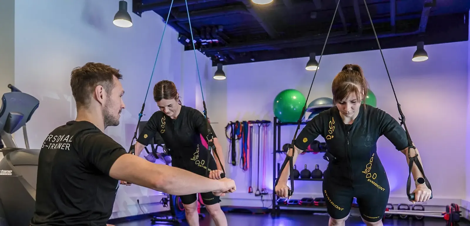 Personal Trainer betreut zwei Personen im EMS-Anzug im Fusion Gym